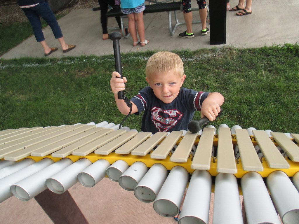 Child playing musical instruments outside the Laurens Library